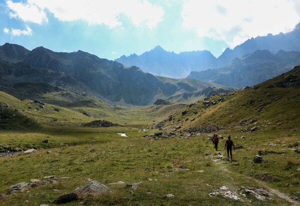 ampio pianoro erboso con alcuni escursionisti. montagne sullo sfondo