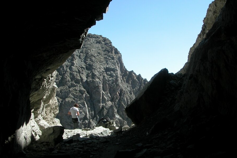 Dall'interno del tunnel si intravedono le montagne circostanti e un escursionista appena fuori dal Buco di Viso