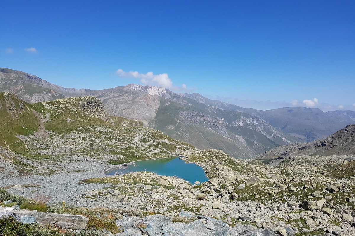 Lago da tipico colore turchese tra le rocce e le praterie alpine. cielo azzurro